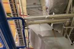 Izolowane rurociągi i trasy kablowe pod stropem sprężarkowni przy wyjściu na dach do dry coolera